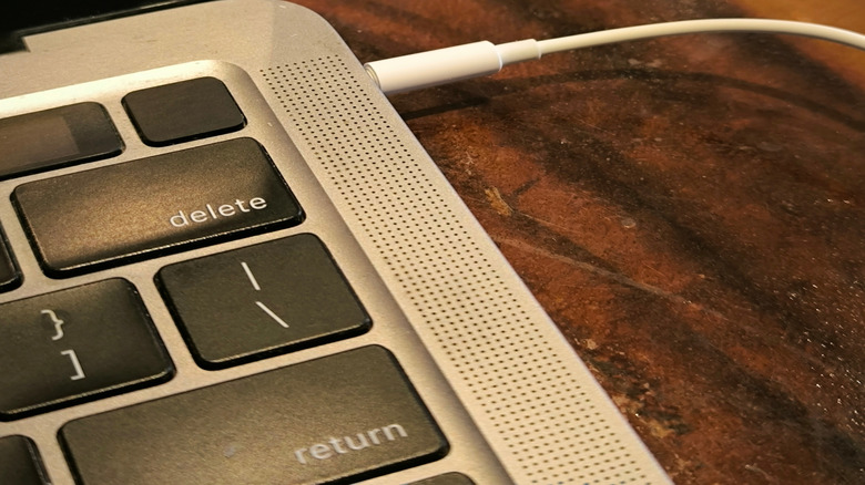 An Apple MacBook with a cable connected to its 3.5mm audio jack