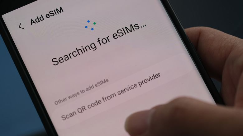 A phone displaying the Add eSIM page with the words Searching for ESIMS on the screen