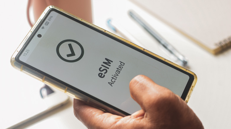 A phone displaying eSIM Activated on its screen, being held by a person