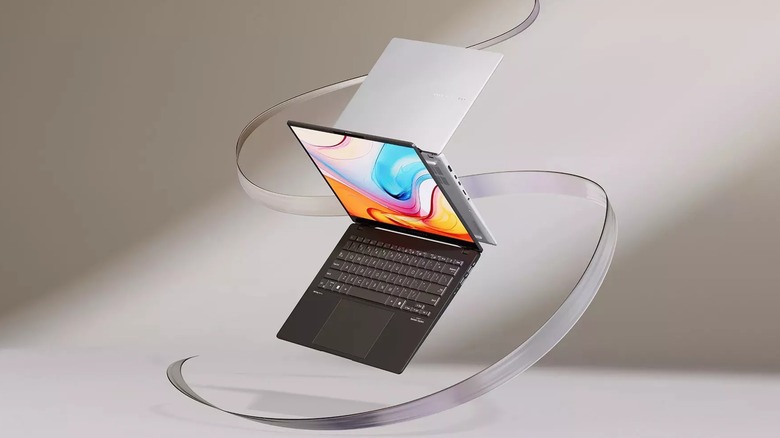 Black and white Asus Vivobook S14 laptops in front of an artistic background