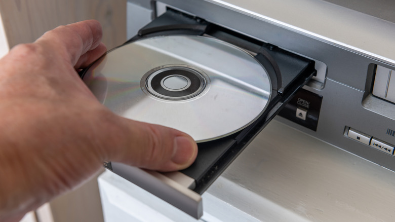 A person inserting a DVD into a DVD player