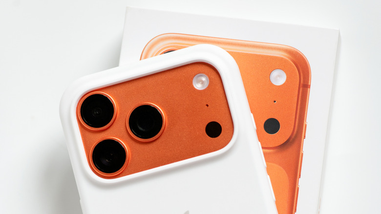 The Cosmic Orange iPhone 17 Pro inside a white protective case, on top of the phone's retail box.