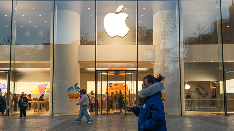 A person walking in front of an Apple retail store