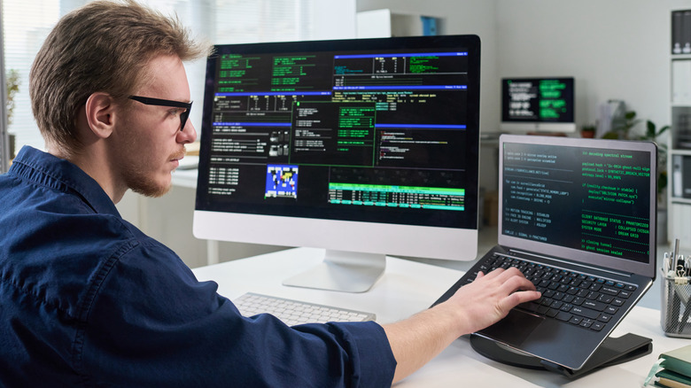 Man working on a laptop with multiple displays