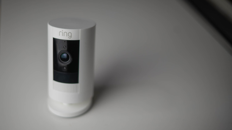 Ring security camera resting on a table indoors in dim lighting.