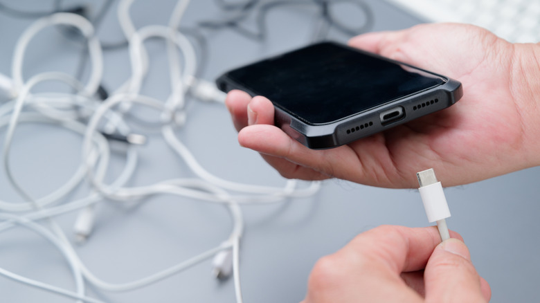 person plugging in charging cable to phone