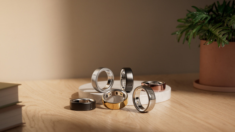 A series of Oura rings of different colors sit scattered across a table.