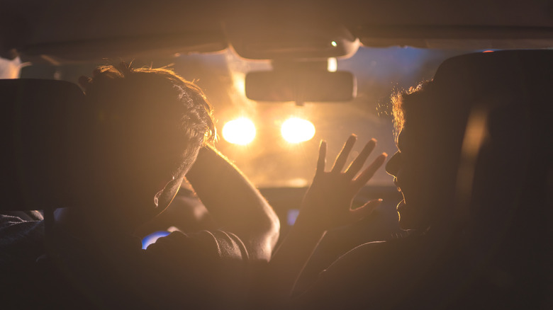 A couple being blinded by a car's headlights at night.