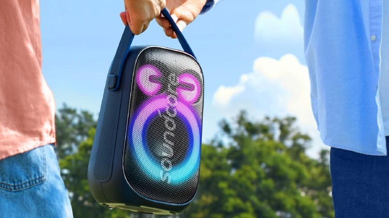 Soundcore Anker Rave Neo 2 speaker with logo on front being passed between users.