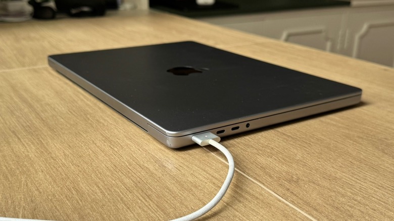 A MacBook Pro on a table being charged via MagSafe