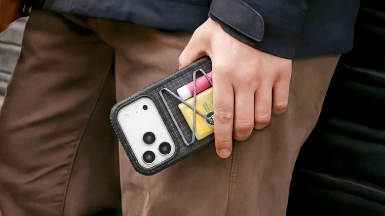 A person holding an iPhone case that has a compartment for personal items.
