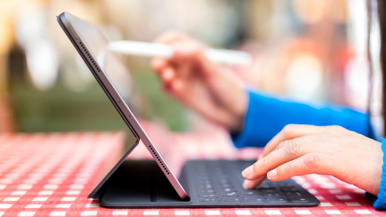 a person using an Apple iPad on a table outdoors