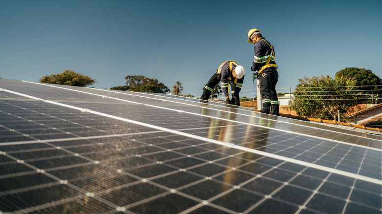 Workers installing solar panels on a roof.