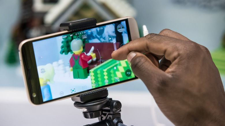 The LG G5 modular smartphone, which is not a tablet, being held on a mobile tripod.