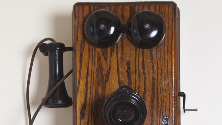 An antique hand-cranked telephone mounted on the wall.