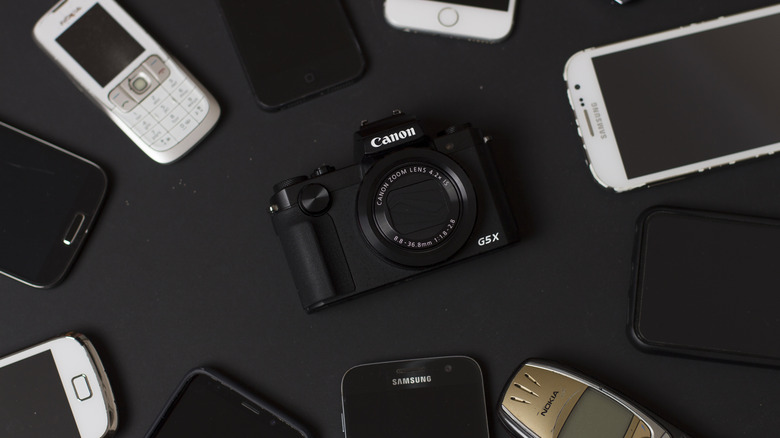 Smartphones surrounding a Canon camera.