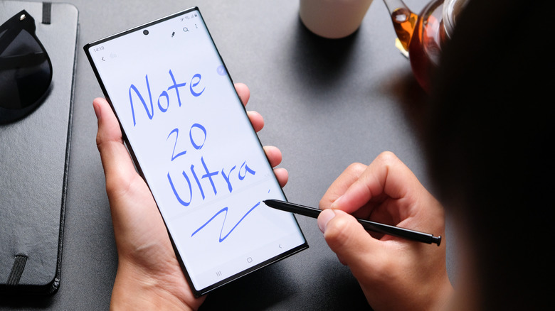 A person writing on a Samsung Note 20 Ultra device using the S Pen stylus