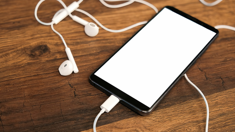 Smartphone with connected USB-C earphones on a wooden table