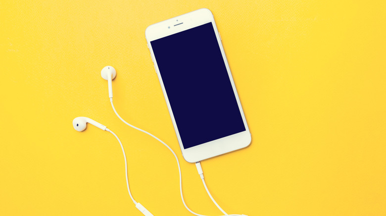 Top down view of smartphone with wired headphones plugged into a physical jack.