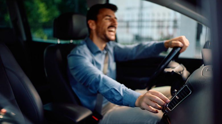 A man adjusting a car radio while driving.