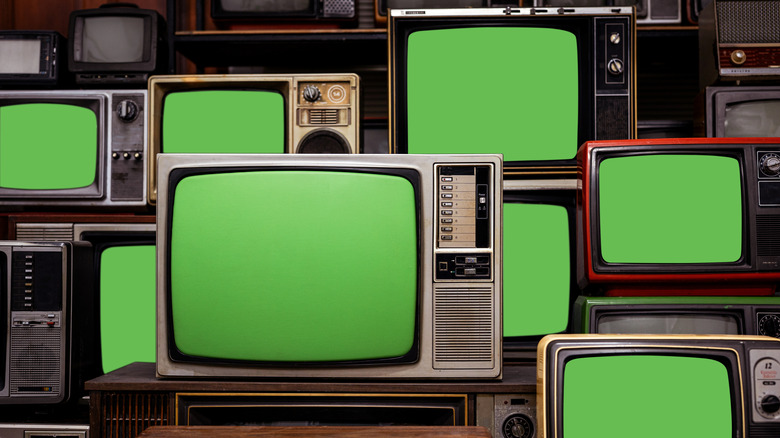 A room full of vintage CRT TVs with green screens on display