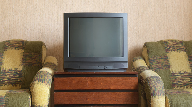 A retro TV on a shelf between two old recliners