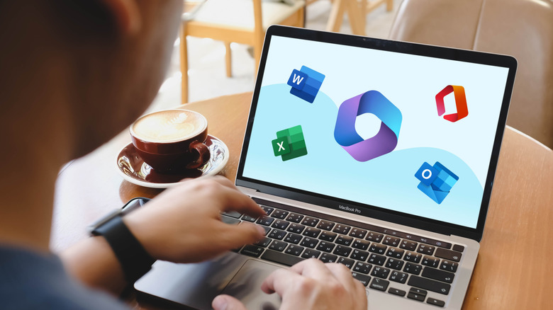 A person using a laptop in a coffee shop with Microsoft 365 logos displayed on the screen