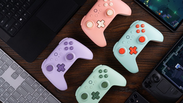 Four 8BitDo Ultimate 2C controllers surrounded by computers and gaming devices