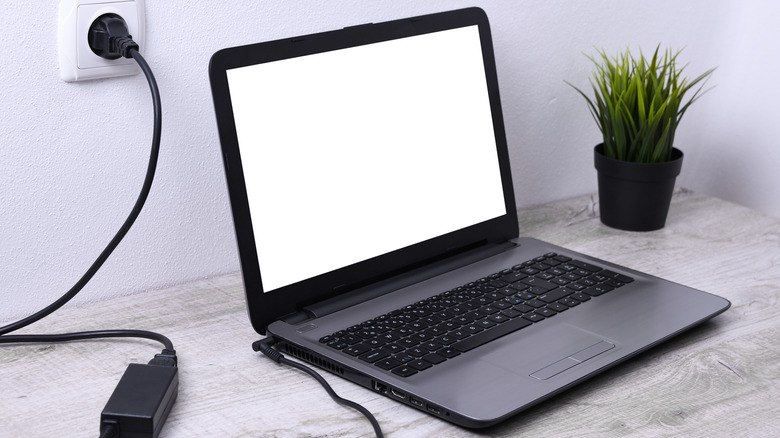 Laptop with charging cable plugged into wall