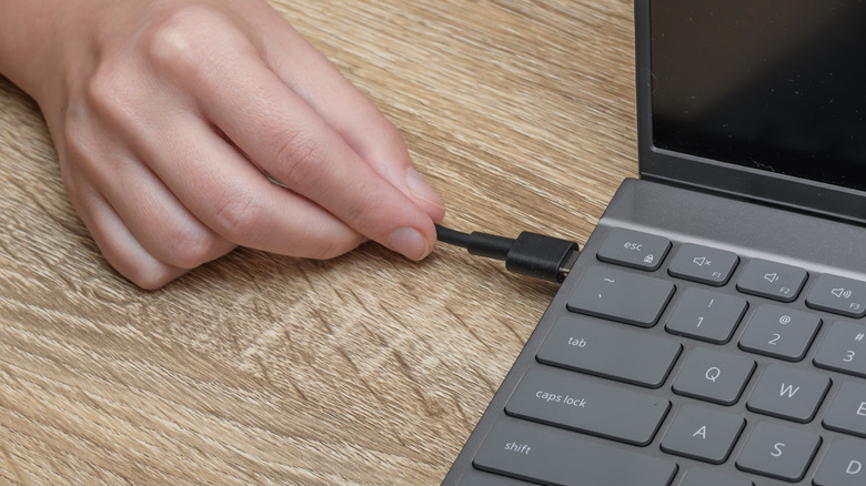 A person connecting a charger to a laptop
