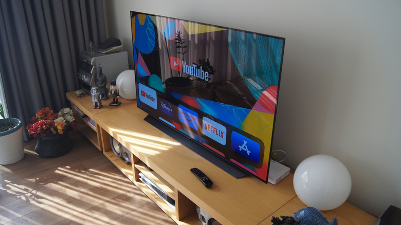 an LG TV on a wooden shelfing while turned on in a furnished room