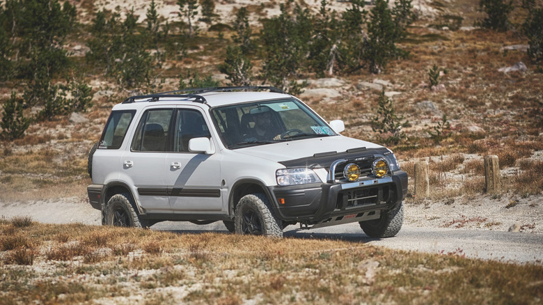 A first-generation Honda CRV SUV modified for off-road use drives on a dirt road in the Deschutes National Forest