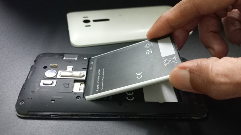 Person removing smartphone battery from shell.