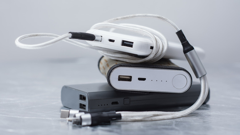 A pile of portable power banks with cables connected.