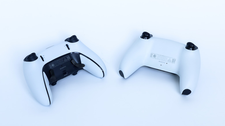 Two PS5 DualSense controllers backward facing to the camera on a white surface