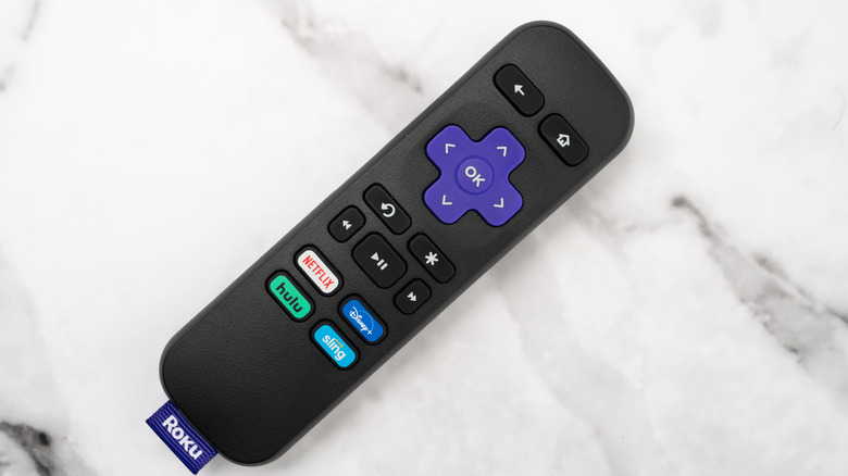 A Roku remote laying on a marble surface.
