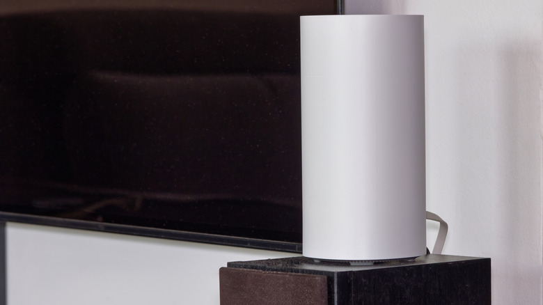 Mesh Wi-Fi node atop a speaker in a living room setting.