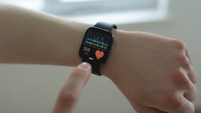 A person checking their pulse and calories burned on a wrist-worn smartwatch.