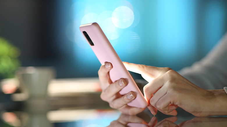 Woman using smartphone with a pink case.
