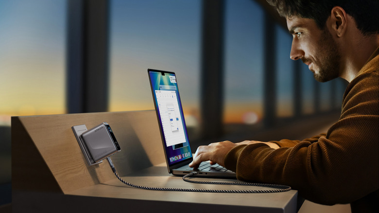 A man in an airport on his laptop plugged into an Anker charger.