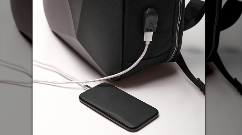 A phone charging from a USB port on a backpack.