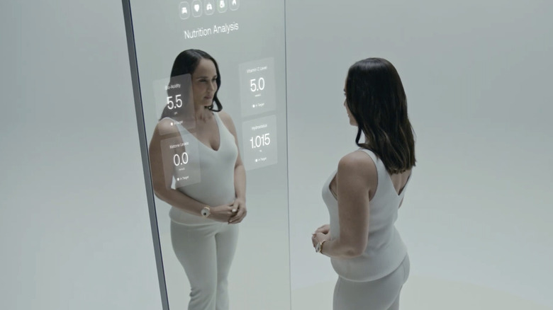 A woman stands in front of a Withings Omnia smart mirror showing nutrition data.