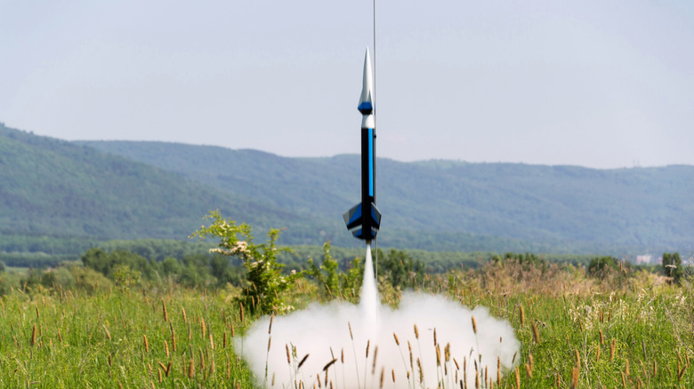 A model rocket launching in a field
