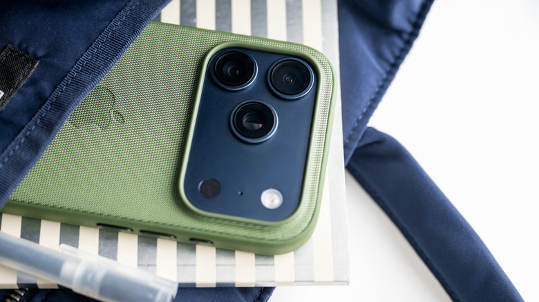 A closeup of the camera cluster on the back of an iPhone in a green case