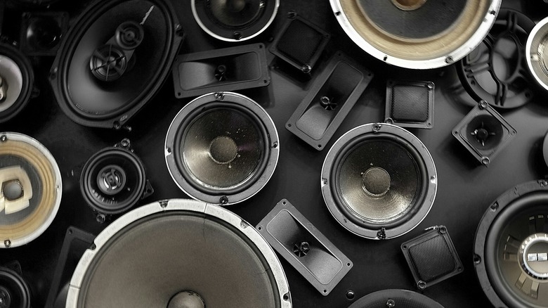 Multiple types of speaker drivers laid out on a dark background.