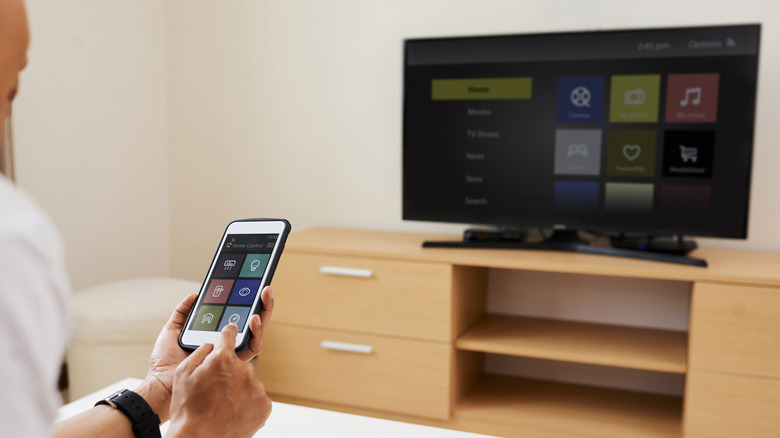 A person using their smartphone as a Bluetooth remote for a TV
