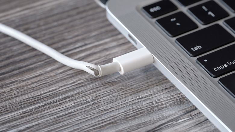 A frayed USB cable connected to a MacBook