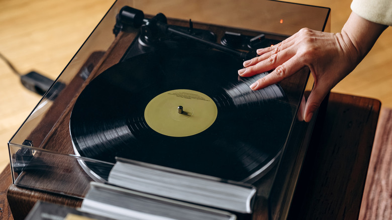 Person closing turntable to play vinyl record