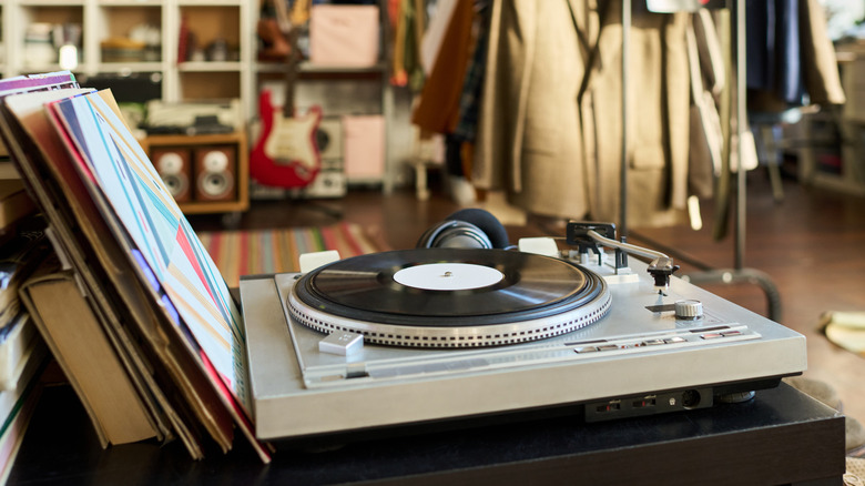 Vinyl record playing on turntable with music gear and other records nearby