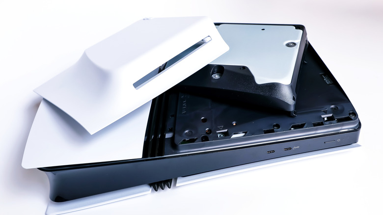PlayStation 5 Pro with disc drive and cover detached in front of white background